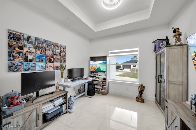 living area featuring a desk, a tray ceiling, light tile patterned floors, and baseboards