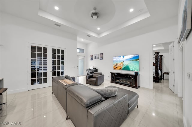 living area featuring french doors, recessed lighting, a raised ceiling, light tile patterned floors, and baseboards