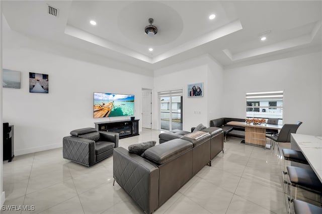 living room featuring a raised ceiling, a towering ceiling, recessed lighting, baseboards, and light tile patterned flooring