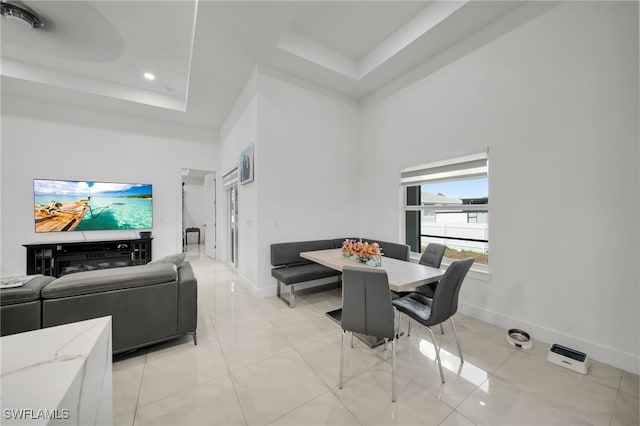 dining room with a raised ceiling, a high ceiling, baseboards, recessed lighting, and light tile patterned floors