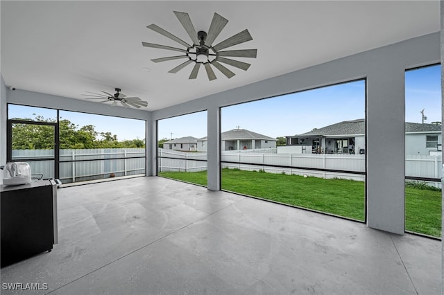 unfurnished sunroom featuring a ceiling fan, healthy amount of natural light, and a residential view