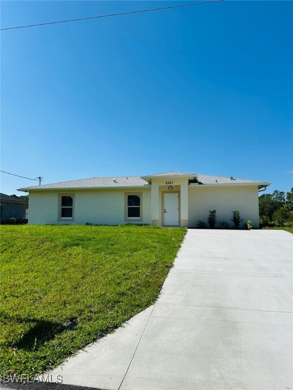 view of front of home with stucco siding, a front lawn, and concrete driveway