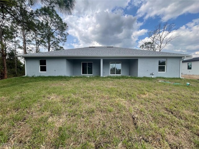 4521/4523 24th St SW, Lehigh Acres, FL 33973 - back of house with stucco siding and a lawn