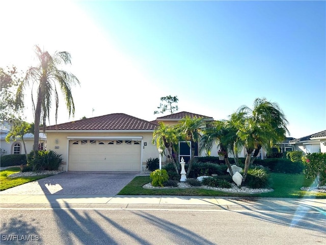 view of front of home featuring an attached garage, driveway, stucco siding, and a tiled roof