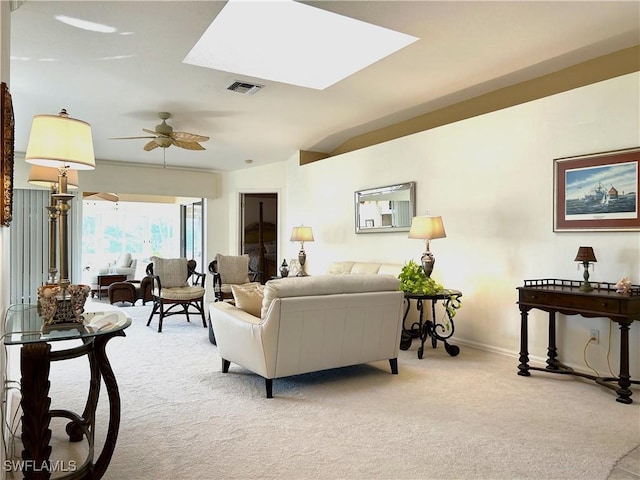 living room featuring light carpet, ceiling fan, baseboards, and a skylight