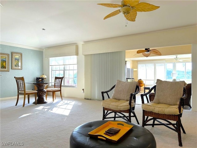 sitting room featuring plenty of natural light, light carpet, ornamental molding, and a ceiling fan