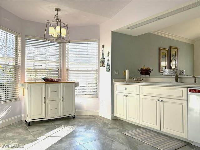 kitchen featuring dishwasher, baseboards, a sink, a chandelier, and decorative light fixtures