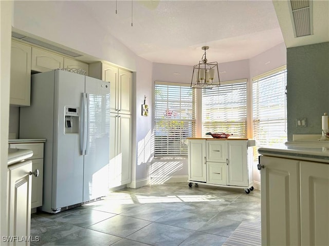 kitchen with white refrigerator with ice dispenser, plenty of natural light, a chandelier, and hanging light fixtures