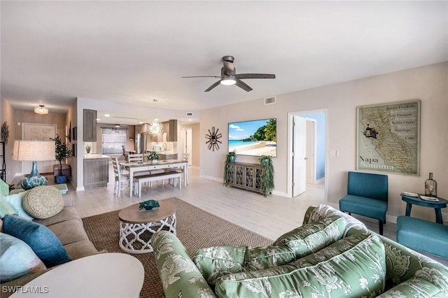 living room with ceiling fan, baseboards, and light wood-style floors