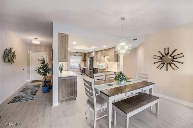 dining space with light wood-style floors, baseboards, a chandelier, a raised ceiling, and recessed lighting