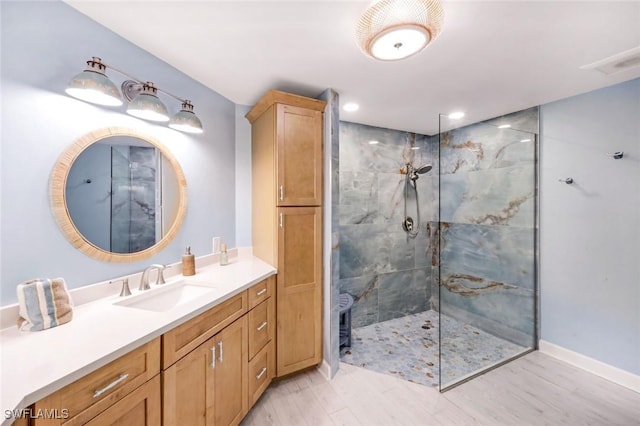 bathroom with a walk in shower, wood finished floors, vanity, baseboards, and recessed lighting