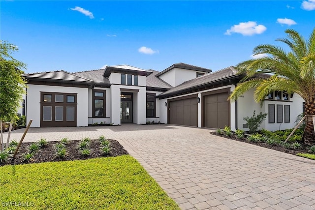 view of front of house with a garage, stucco siding, decorative driveway, and a tile roof