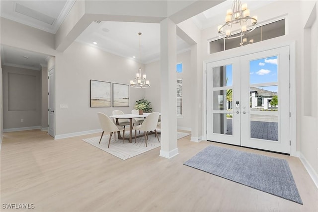 foyer entrance featuring a chandelier, french doors, baseboards, light wood-style floors, and crown molding