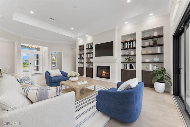 living room with a lit fireplace, light wood-style flooring, built in shelves, french doors, and recessed lighting