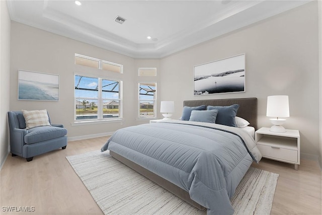 bedroom with light wood-style flooring, baseboards, a raised ceiling, recessed lighting, and crown molding