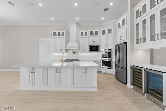 kitchen with appliances with stainless steel finishes, beverage cooler, light countertops, crown molding, and backsplash