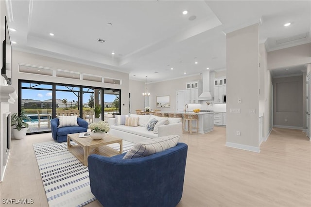 living room with a raised ceiling, recessed lighting, light wood-style floors, crown molding, and baseboards