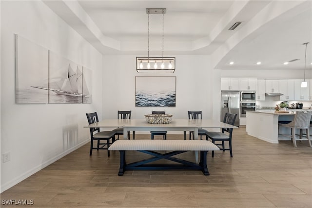 14860 Cherry Blossom Way, Punta Gorda, FL 33955 - dining area featuring a raised ceiling, light wood-style flooring, recessed lighting, baseboards, and arched walkways