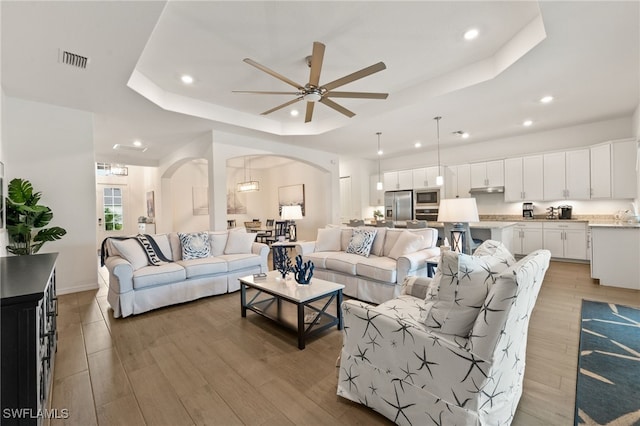 14860 Cherry Blossom Way, Punta Gorda, FL 33955 - living area featuring a tray ceiling, arched walkways, recessed lighting, a ceiling fan, and light wood-type flooring