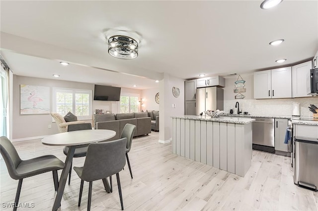 114 Lovers Ln, Fort Myers Beach, FL 33931 - kitchen with stainless steel dishwasher, a sink, a center island, light wood finished floors, and tasteful backsplash