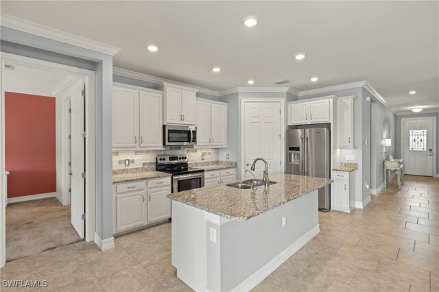 kitchen featuring stainless steel appliances, a sink, white cabinets, baseboards, and a kitchen island with sink