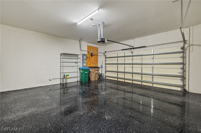 garage featuring a garage door opener, concrete block wall, and electric panel