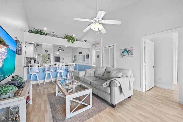 living area featuring high vaulted ceiling, light wood finished floors, ceiling fan, baseboards, and recessed lighting