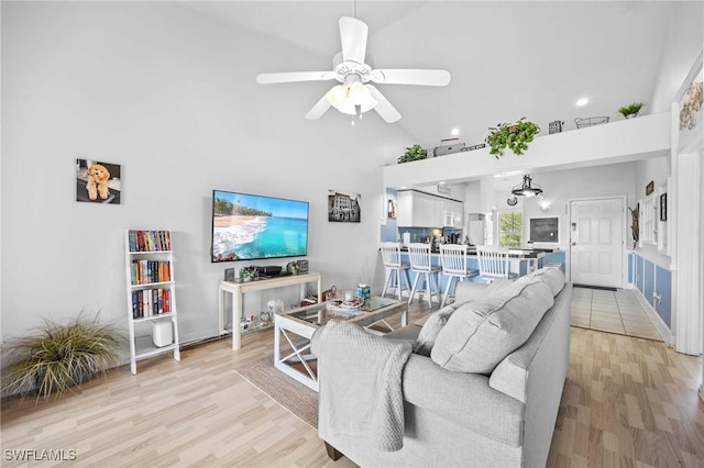 living room with high vaulted ceiling, a ceiling fan, light wood finished floors, recessed lighting, and baseboards