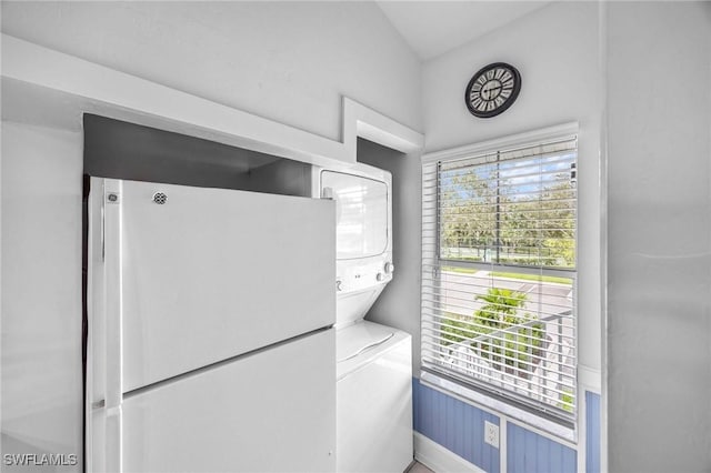 laundry area featuring stacked washer / dryer and baseboards