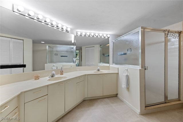 bathroom featuring a stall shower, double vanity, tile patterned flooring, and baseboards