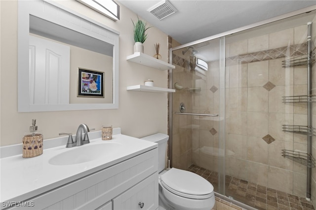 bathroom featuring toilet, a shower stall, and vanity