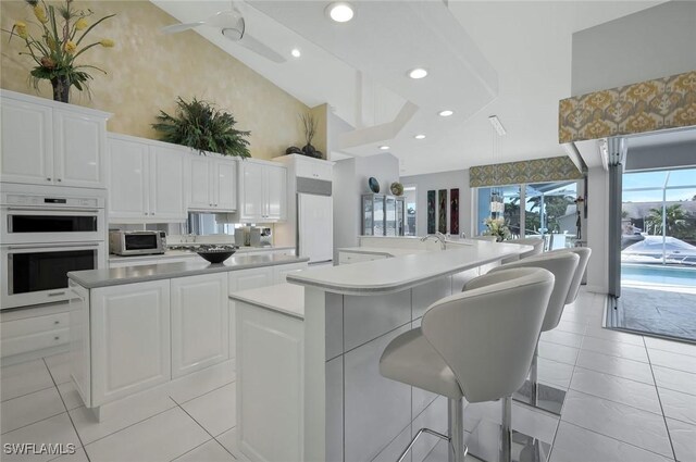 1428 SW 52nd Ln, Cape Coral, FL 33914 - kitchen featuring a spacious island, high vaulted ceiling, double oven, light tile patterned flooring, and white cabinets