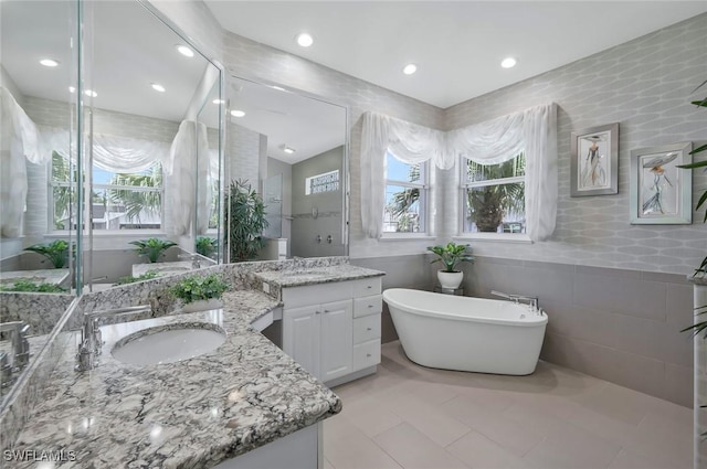 1428 SW 52nd Ln, Cape Coral, FL 33914 - bathroom featuring tile walls, plenty of natural light, a freestanding bath, two vanities, and recessed lighting