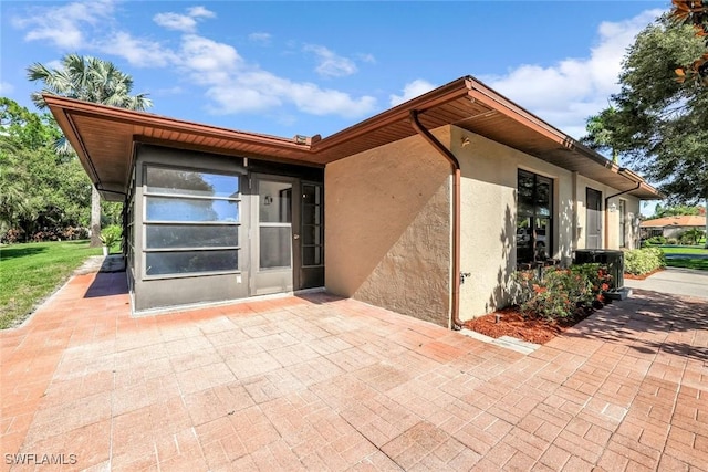 rear view of property featuring a patio, stucco siding, and central AC