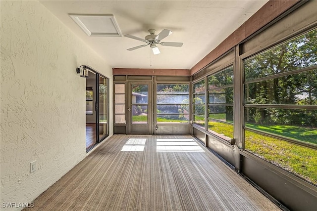 unfurnished sunroom featuring ceiling fan, a water view, and healthy amount of natural light
