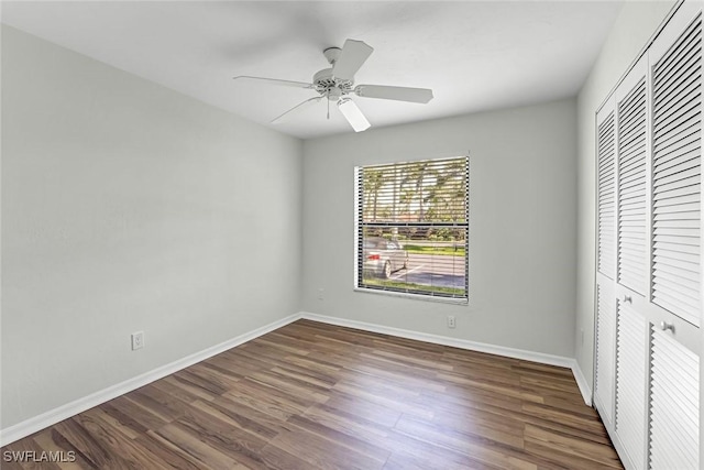 unfurnished bedroom featuring wood finished floors, a closet, baseboards, and a ceiling fan