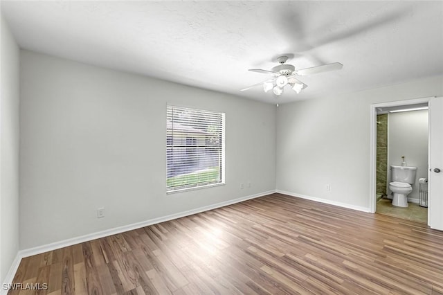 empty room featuring wood finished floors, baseboards, and a ceiling fan