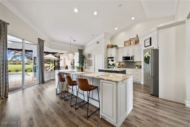 11730 Rosemount Dr, Fort Myers, FL 33913 - kitchen with appliances with stainless steel finishes, a large island with sink, dark wood-style floors, white cabinetry, and lofted ceiling