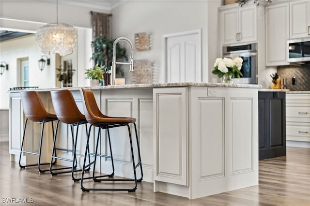 11730 Rosemount Dr, Fort Myers, FL 33913 - kitchen featuring appliances with stainless steel finishes, a chandelier, wood finished floors, a breakfast bar, and tasteful backsplash