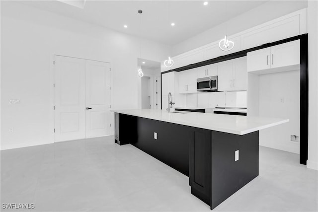 1432 Euclid Ave, Lehigh Acres, FL 33972 - kitchen featuring stainless steel microwave, white cabinetry, a spacious island, light countertops, and recessed lighting