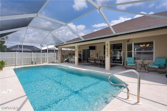 view of swimming pool with a patio, fence, outdoor dining area, and a lanai