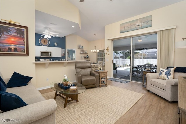 living room featuring ceiling fan, light wood finished floors, a chandelier, high vaulted ceiling, and baseboards