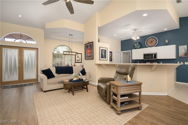 living room featuring ceiling fan, baseboards, light wood finished floors, recessed lighting, and french doors