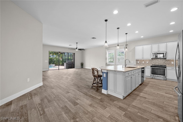 10626 Essex Square Blvd, Fort Myers, FL 33913 - kitchen with appliances with stainless steel finishes, white cabinetry, open floor plan, a sink, and an island with sink
