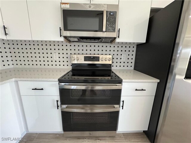 3408 SW 17th Pl, Cape Coral, FL 33914 - kitchen featuring stainless steel appliances, white cabinetry, light wood finished floors, and backsplash