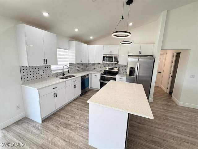 kitchen with appliances with stainless steel finishes, a sink, a center island, baseboards, and decorative backsplash