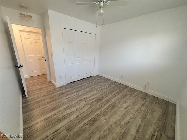 unfurnished bedroom with wood finished floors, baseboards, and a closet