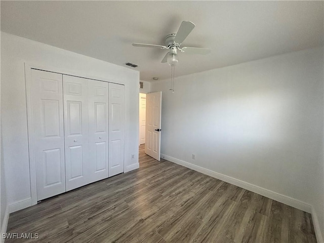 unfurnished bedroom featuring wood finished floors, baseboards, a closet, and ceiling fan