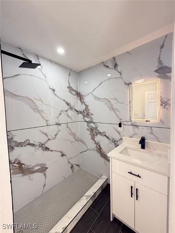 bathroom with vanity and a marble finish shower