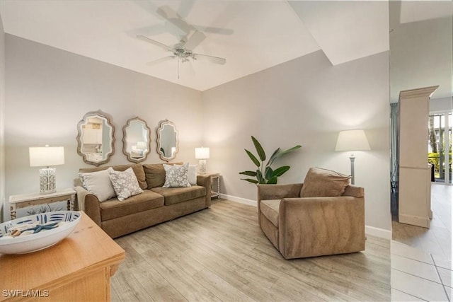 living room featuring a ceiling fan, baseboards, and light wood-type flooring
